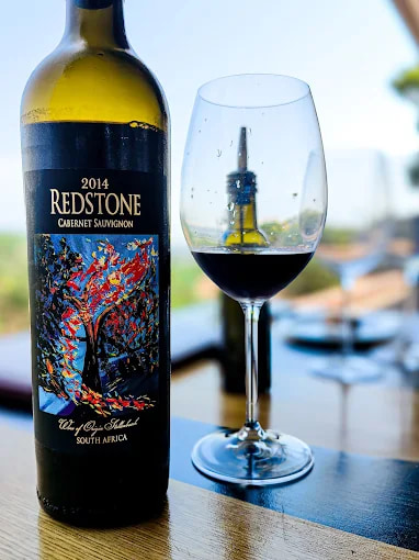 A bottle of 2014 Redstone Cabernet Sauvignon next to a glass of red